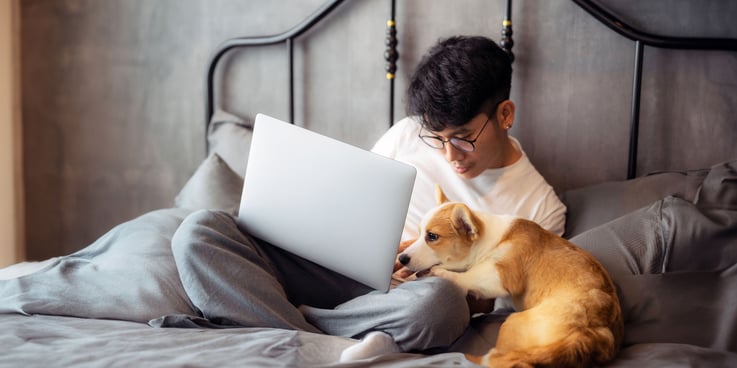 Man working on a laptop beside his dog
